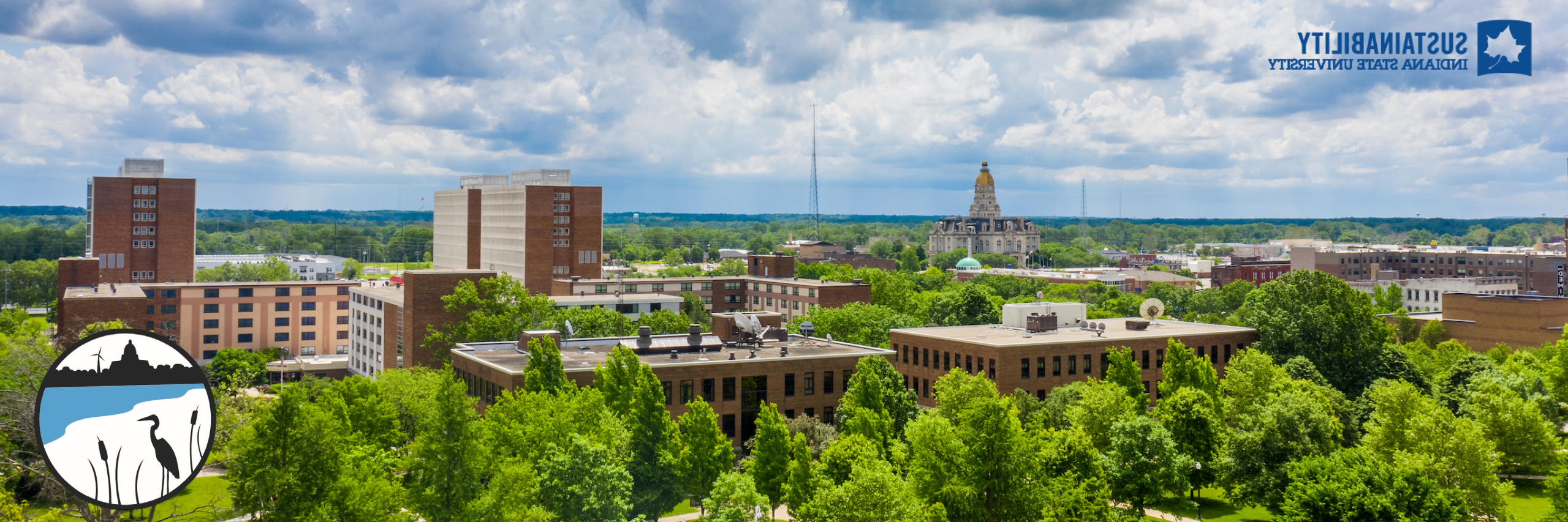 Overview of campus with green trees and visible buildings in the background. The logo for the office of sustainability is in the top left corner and the circular mark is in the bottom right. 